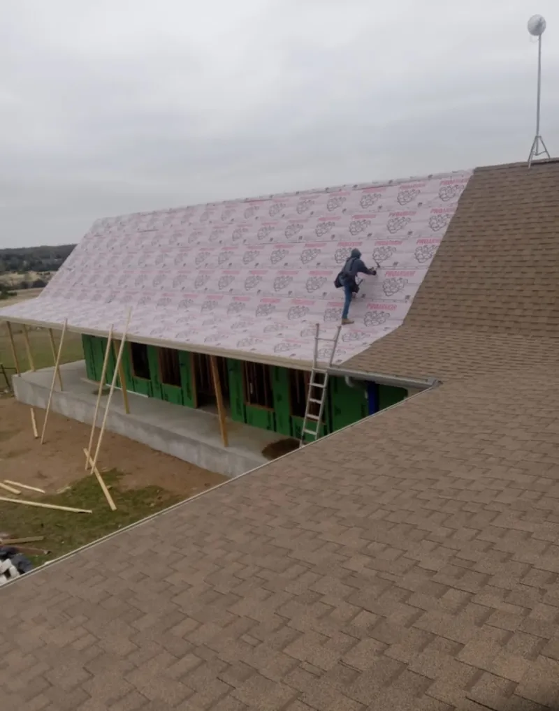 Worker preparing underlayment for a metal roof installation in Kimberly